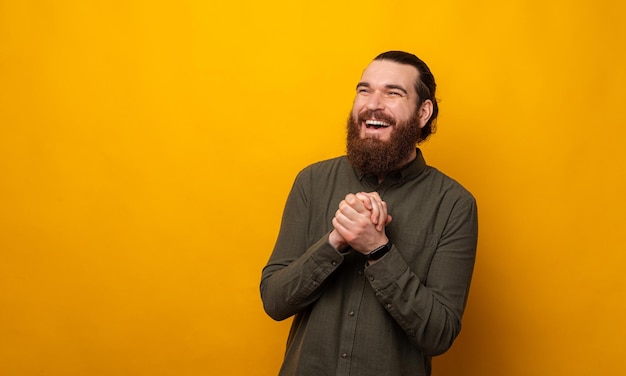 This is how happiness looks like A man laughing and holding hands together Studio shot over yellow background Panorama with copy space