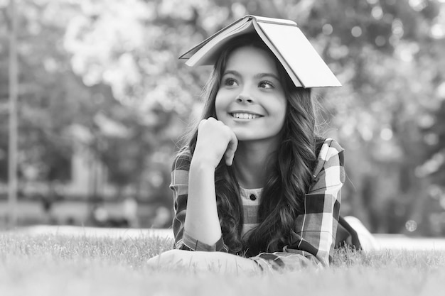 This is my reading house Happy child hold book on head lying on green grass Lending library Reading and literacy education School library Bibliotheca Information and knowledge September 1