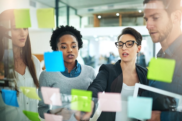 This is our best strategy for success Cropped shot of coworkers using sticky notes on a glass wall during a meeting