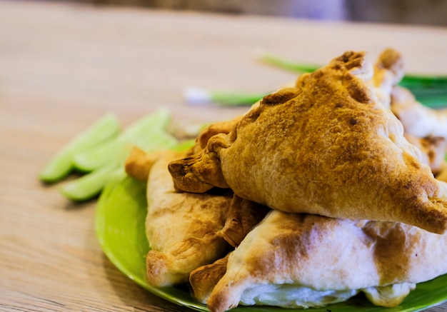 This is a real Uzbek samsa on a plate with vegetables and green onions. National cuisine