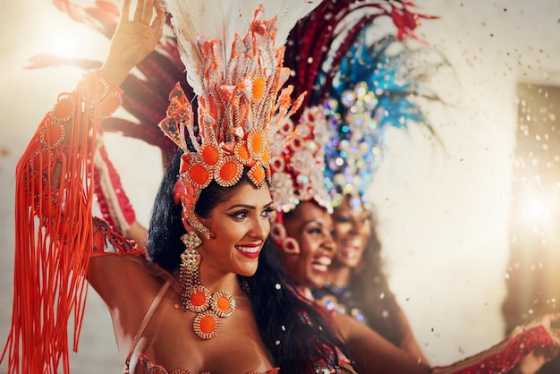 This is their show Shot of a group of female dancers wearing vibrant costumes while dancing to music inside of a busy nightclub