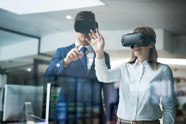 This is what the future of business looks like Multiple exposure shot of two coworkers brainstorming together in the office while wearing VR headsets