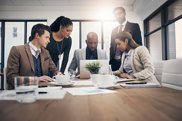 This is what our competitors are looking like Shot of a group of young businesspeople using a laptop together during a meeting in a modern office