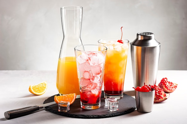 This photo shows the process of making an alcoholic cocktail Tequila Sunrise with ice orange juice