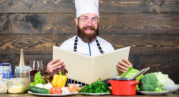 This recipe is just perfect Man bearded hipster read book recipe near table fresh vegetables Culinary arts Recipe to cook healthy food Vegetarian recipe Experienced chef cooking excellent dish