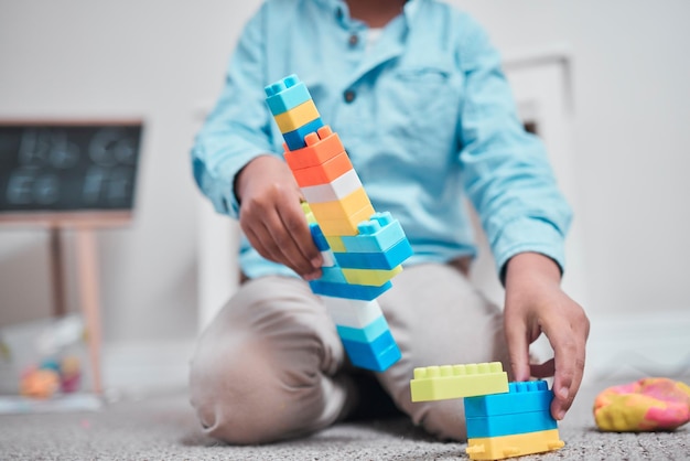 This will keep them entertained for ages. Shot of a young boy playing with building blocks in a room.