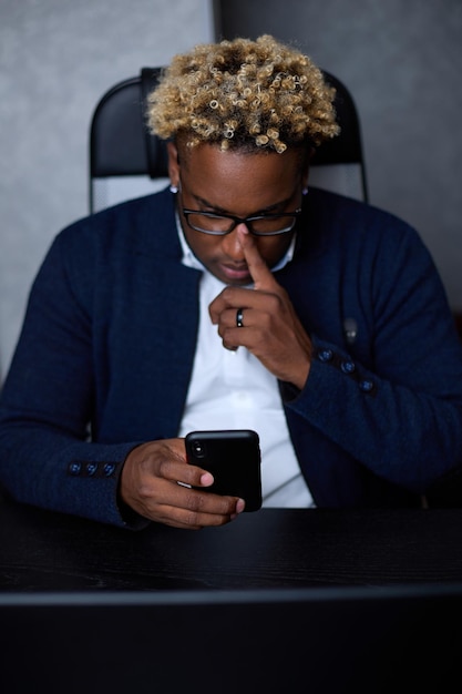 Thoughtful African man with a worried expression uses a mobile phone