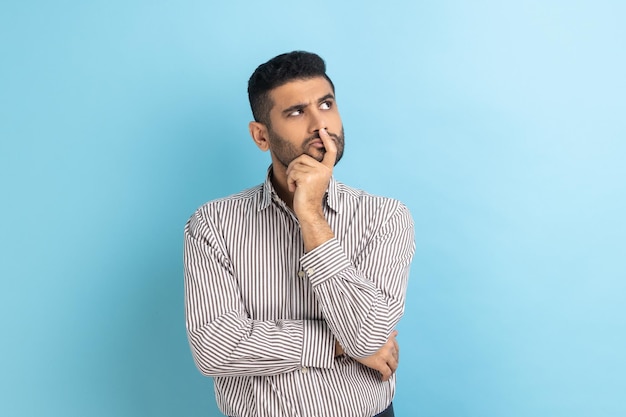 Thoughtful bearded businessman holding his chin and pondering idea confused not sure about solution