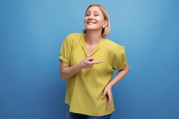 Thoughtful blonde mature woman smiling and emotional on studio background