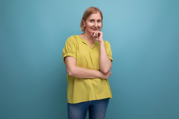 Thoughtful blonde mature woman in yellow tshirt with emotions of surprise