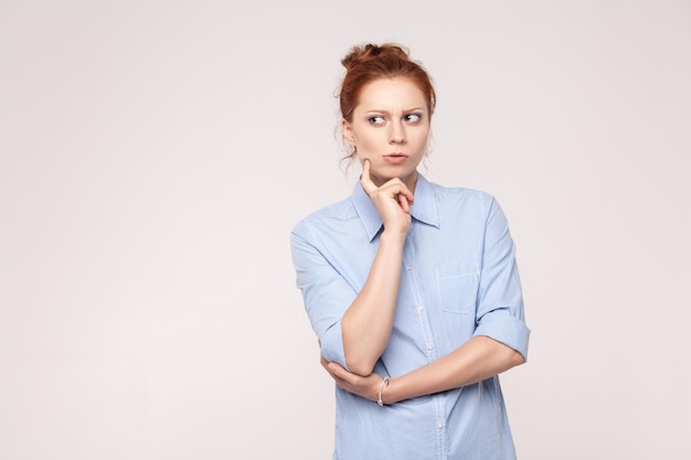 Thoughtful business woman looking away while standing against graywall