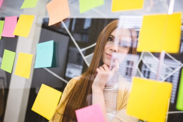 Thoughtful businesswoman looking on sticky notes