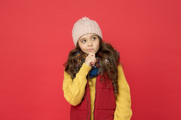 Thoughtful child girl with long hair and warm clothing, dreaming.