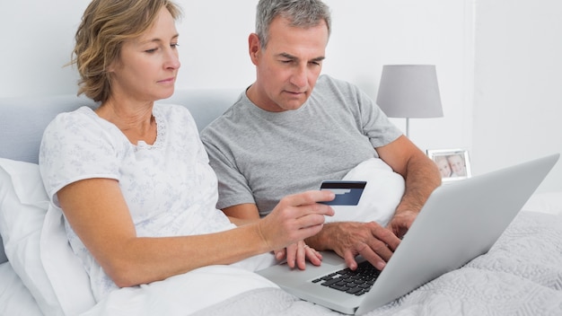 Thoughtful couple using their laptop to buy online