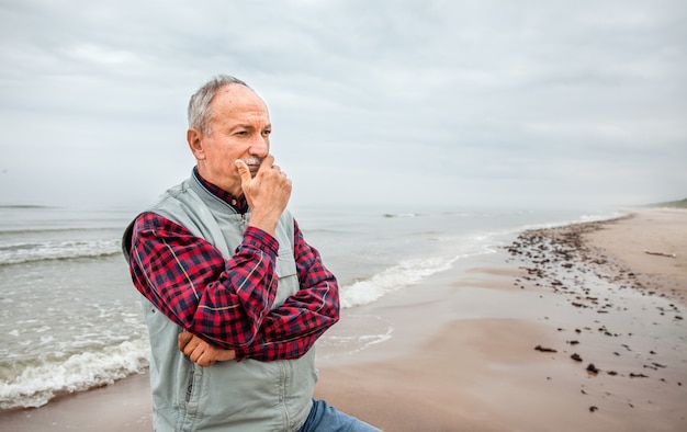 Thoughtful elderly man standing on the beach