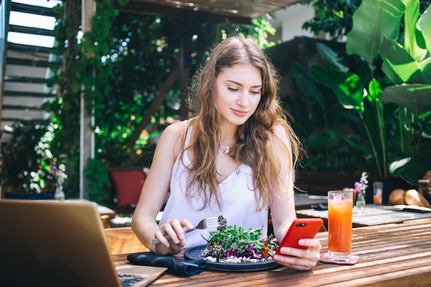 Thoughtful female messaging on cellphone while having lunch in restaurant