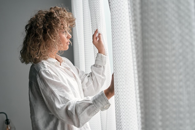 Photo thoughtful female at window in light