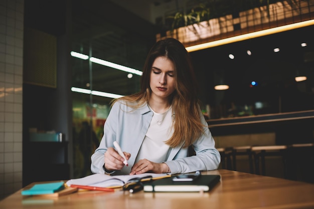 Thoughtful hipster girl sitting at cafeteria while working on design project