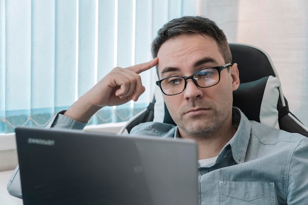 Thoughtful it developer thinking about fixing software bugs on netbook contemplative male student watching tutorial on web site learning online via laptop computer Focus on work employee in office