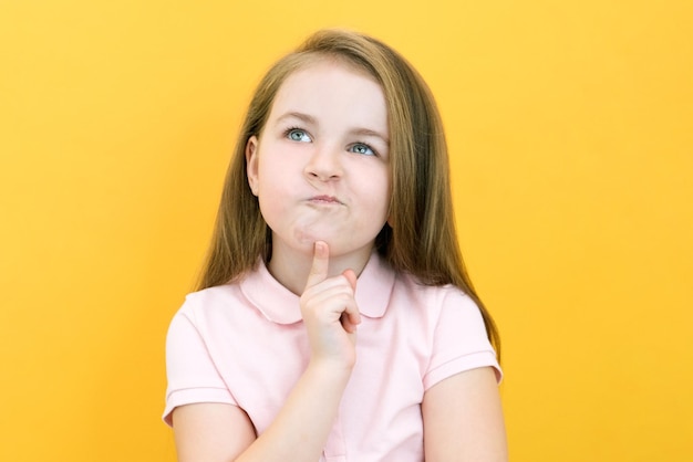 Thoughtful little girl touching observation chin thoughtful cute daughter making decision imagining thought posing isolated over yellow background