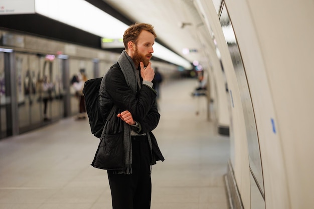 Thoughtful man looking at subway train traffic map at station