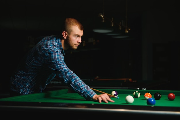 Thoughtful man plays billiards. Billiard room on the background.