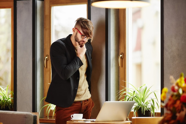 Thoughtful man standing at notebook