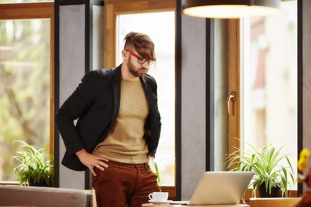 Thoughtful man standing at notebook