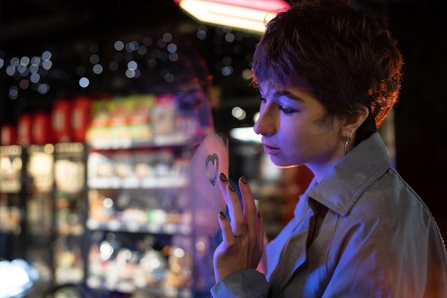 Thoughtful melancholic woman draw heart on steamy wet window think of boyfriend love relationship