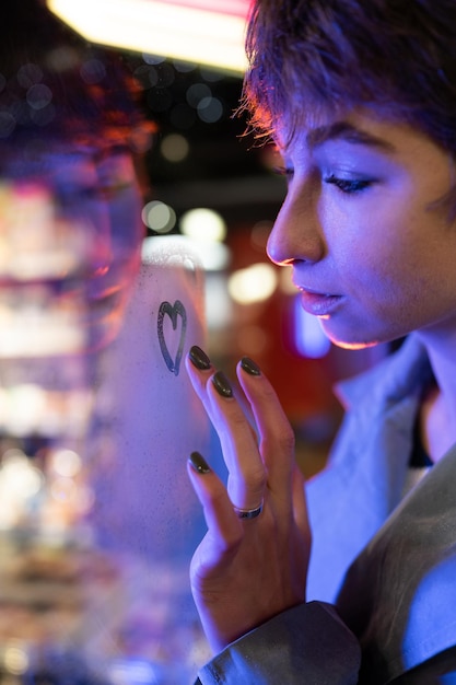 Thoughtful melancholic woman draw heart on steamy wet window think of boyfriend love relationship