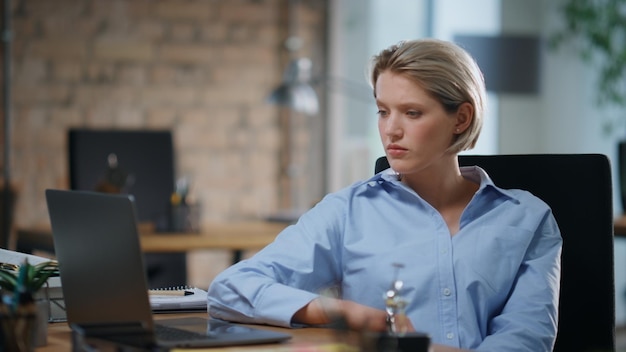 Thoughtful office employee sitting empty office looking laptop screen close up