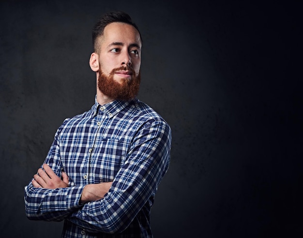 Thoughtful redhead bearded hipster male with crossed arms, dressed in a blue fleece shirt.