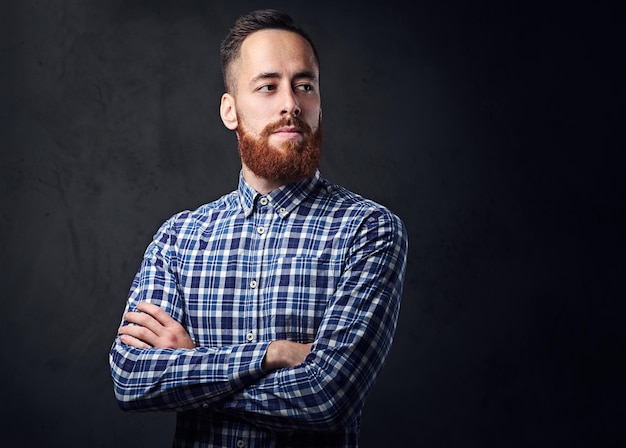 Thoughtful redhead bearded hipster male with crossed arms, dressed in a blue fleece shirt.