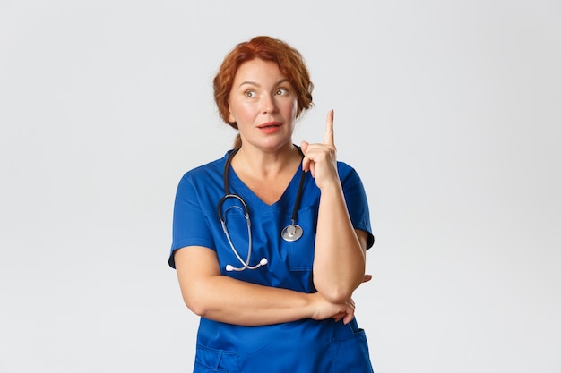 Thoughtful redhead middle-aged nurse, doctor in scrubs have assumption or suggestion