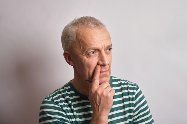 Thoughtful senior man on gray background copy space