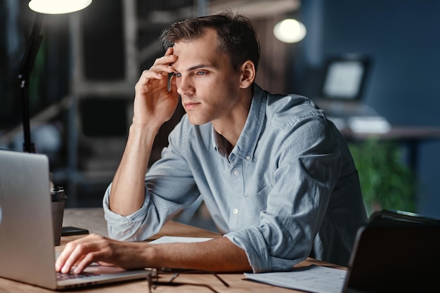 Thoughtful tired businessman works at night in the office