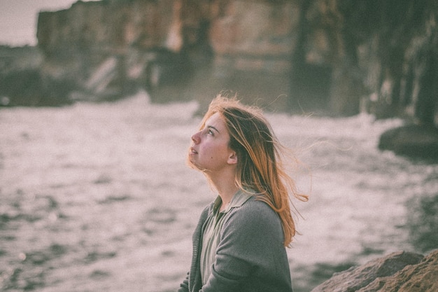 Photo thoughtful woman looking away against rock formation