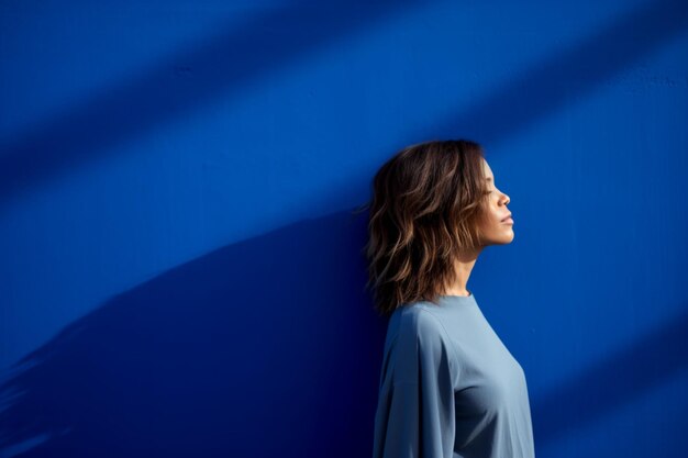 Photo thoughtful woman standing against blue wall