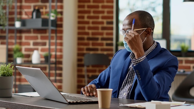 Thoughtful worker brainstorming ideas to create project plan with online statistics. Uncertain employee feeling pensive and thinking about new business startegy during pandemic.