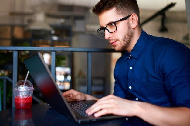 Thoughtful young attractive hipster freelancer working remotely on laptop in loft cafe businessman