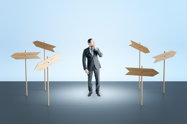 Photo thoughtful young european businessman standing outside with abstract empty wooden signs direction and solution concept