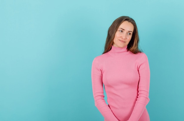 Thoughtful young girl is looking at right on blue background