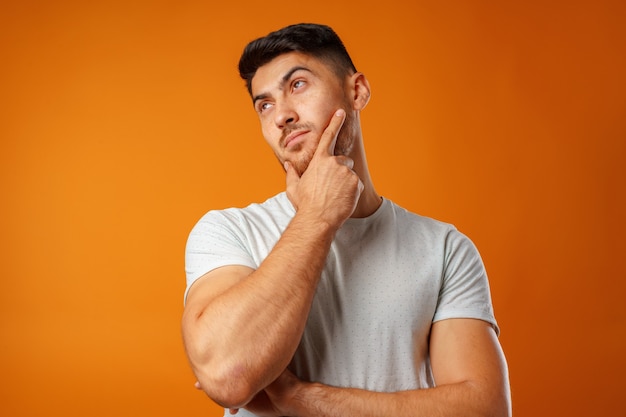 thoughtful young man touching his chin close up