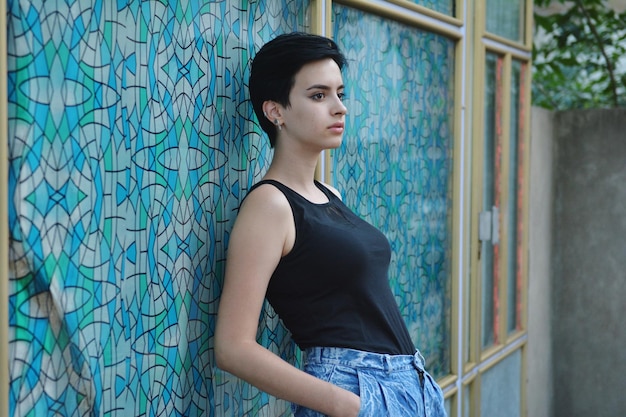 Photo thoughtful young woman looking away while standing against wall