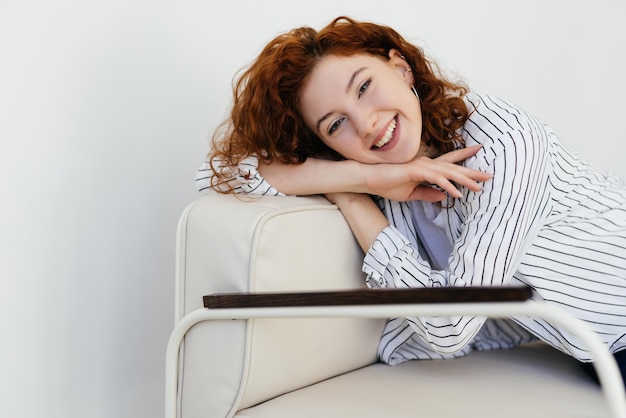 Thoughtful young woman staring intently ahead at the camera relaxes on a sofa at home