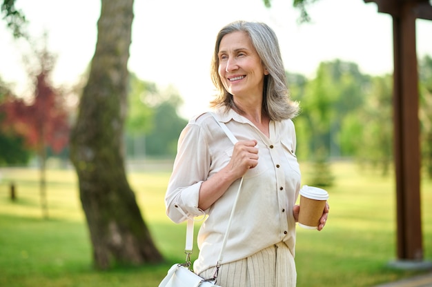 Thoughtfully smiling adult woman with coffee