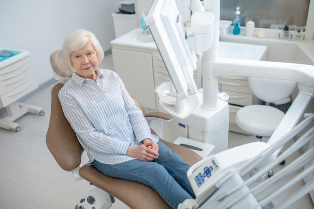 At thre doctors. Gray-haired woman sitting at the dentists office and waiting for the doctor