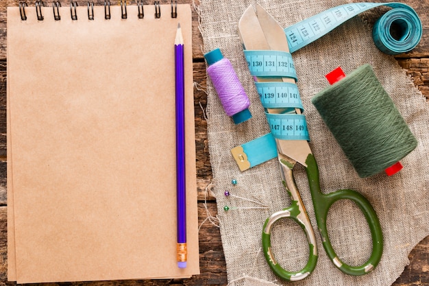 Thread, scissors, measuring tape and a notebook for notes on the wooden 