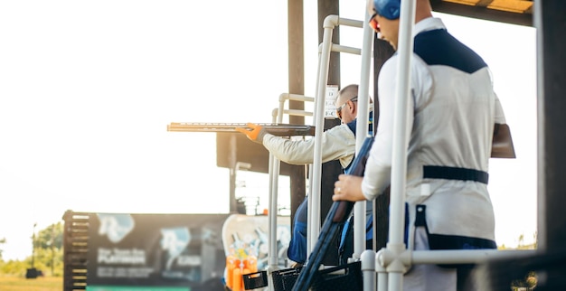 Three adult mans in sunglasses protective headphones and a rifle vest practicing fire weapon shoot