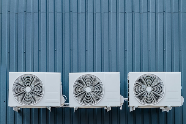 Three air conditioner outdoor units on a blue wall. Copy-space.